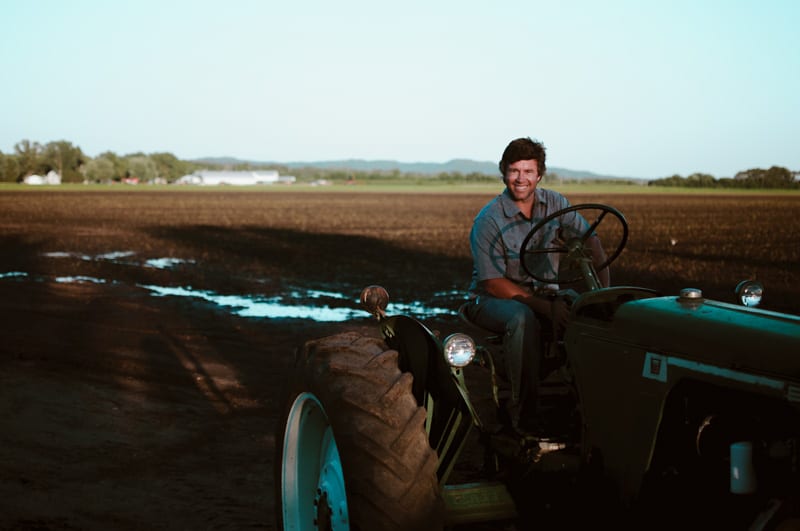 A farmer on a tractor in a field at dusk, from La Crosse Distilling Co.’s photography